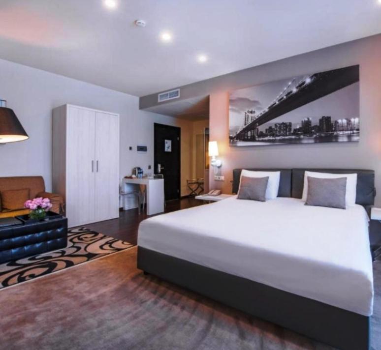 a bedroom with a large white bed and a desk at Pegass hotel in Yerevan