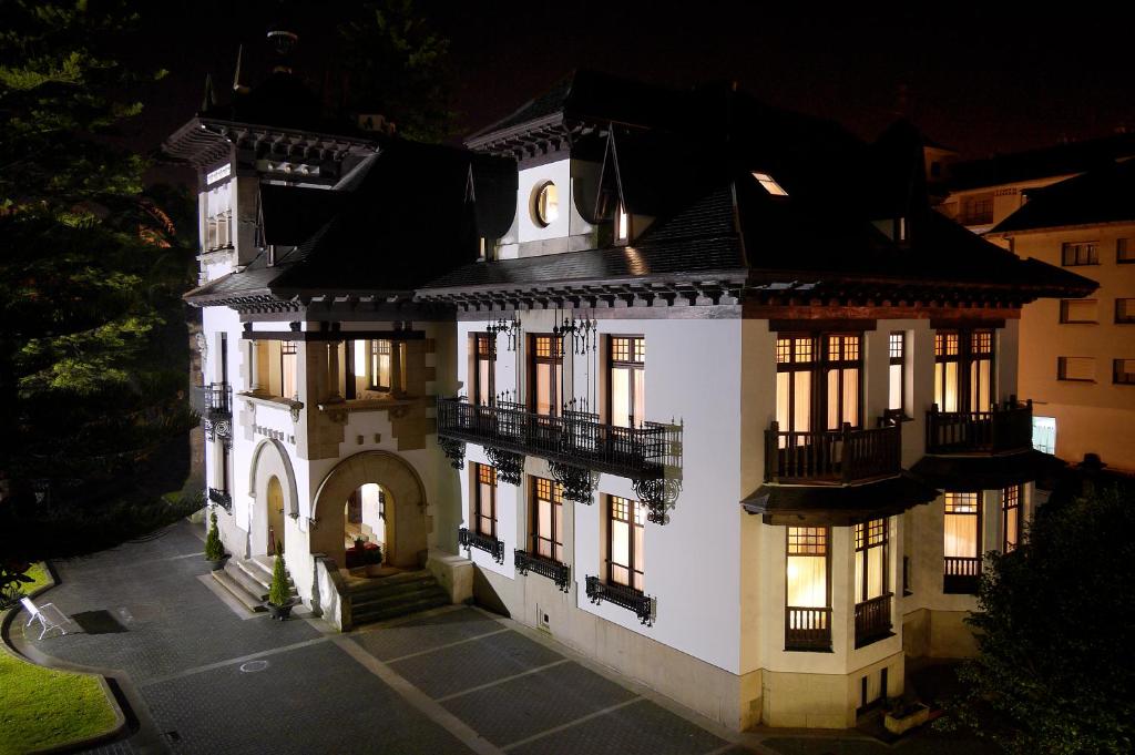 ein großes weißes Haus in der Nacht mit eingeschaltetem Licht in der Unterkunft Palacio Arias in Navia