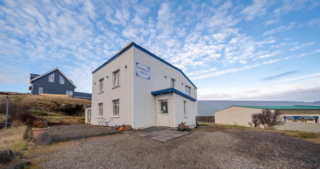 a white building with a blue roof on a hill at Guesthouse Mikael in Höfn