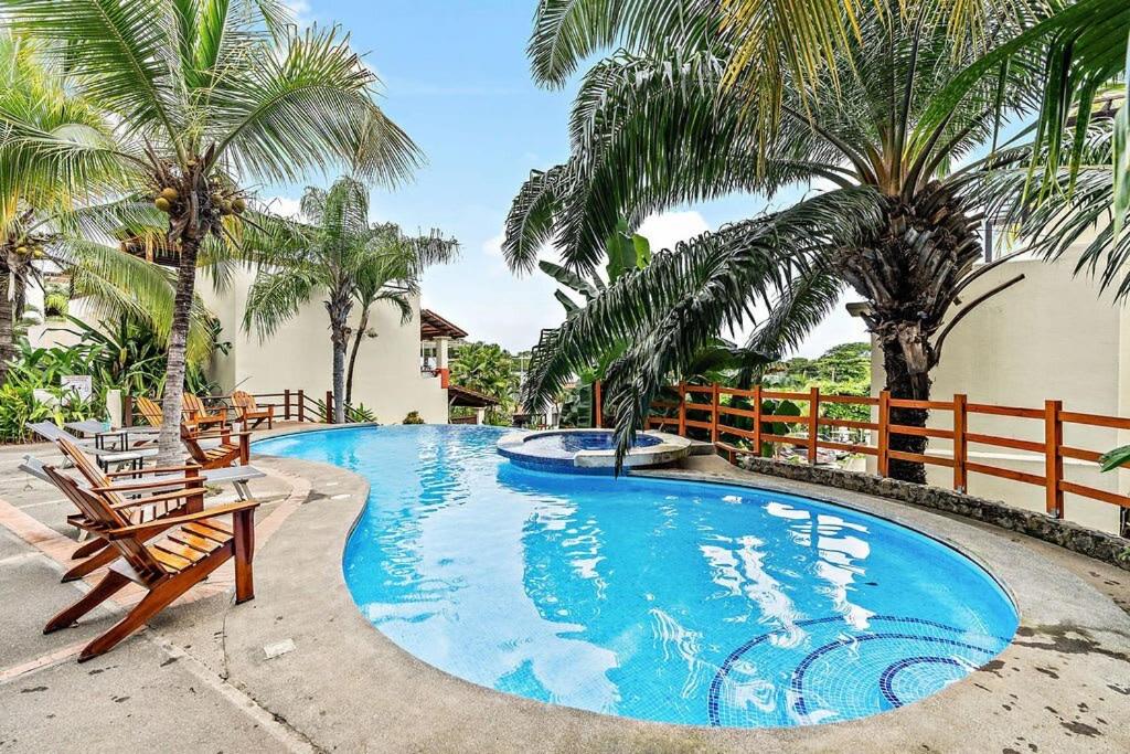 una piscina con dos sillas y palmeras en Colorful & Private 2-Bedroom Condo Just a Short Walk from the Beach, en Coco