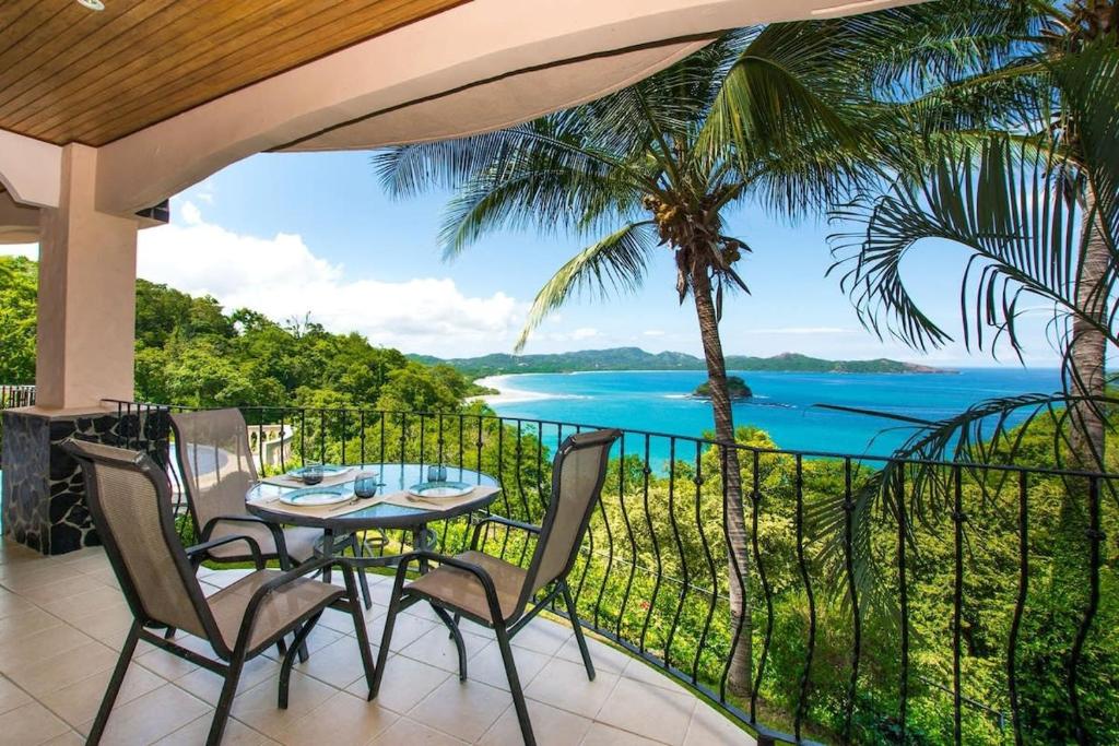 a table and chairs on a balcony with a view of the ocean at Beautiful Condo in Peaceful Cliffside Location with a Private Balcony & Stunning Ocean and Mountain Views in Playa Flamingo