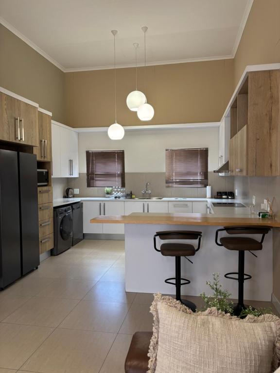eine Küche mit einer großen Insel mit zwei Barhockern in der Unterkunft The Oryx Luxury Apartment in Windhoek