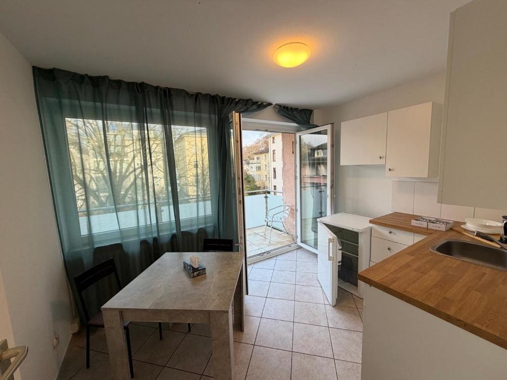 eine Küche mit Tisch und Spüle und Fenster in der Unterkunft MonoApartment in Frankfurt am Main