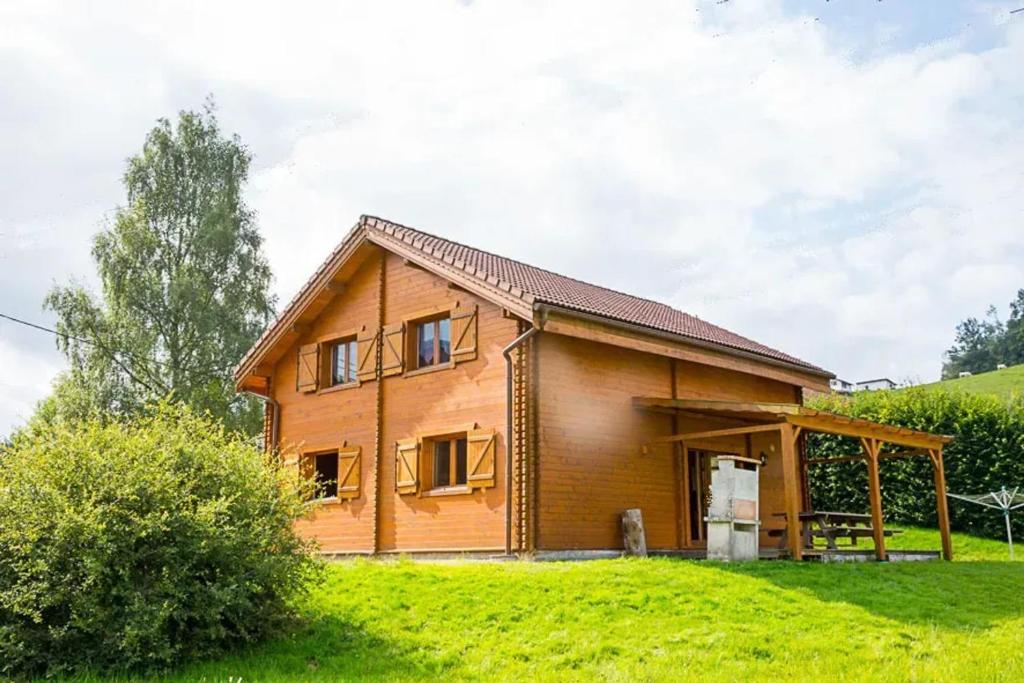 莱托利Chalet spacieux à Le Tholy avec vue montagne的一座位于山丘上的木屋,拥有绿色的田野