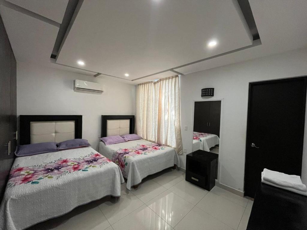 Un dormitorio con dos camas y una ventana. en Casa Hannia 30 huéspedes Cerca de la playa Alberca, en Acapulco