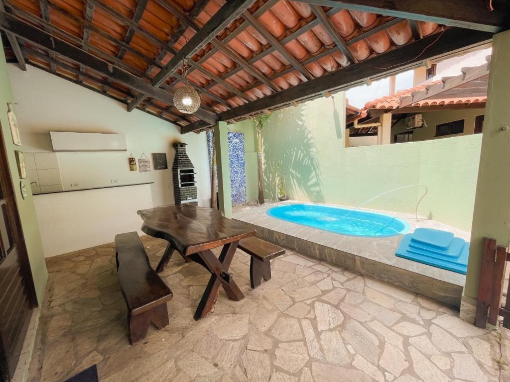 Casasveraneio casa top com 3 suítes com ar condicionado a 100 m da Praia - Barra de São Miguel, 7 minutos do gunga e 3 da praia bonita e conchas ! Área gourmet com piscina privativa e churrasqueira! condomínio com muito verde e piscina de 10m! في بارا دي ساو ميجيل: فناء مع طاولة ومسبح