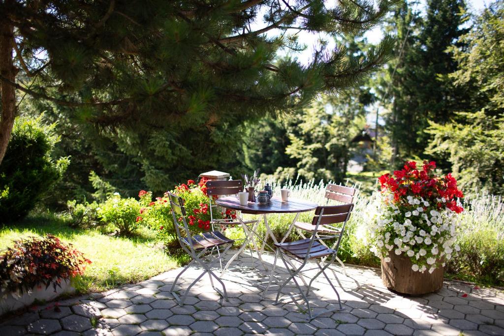 a table and chairs in a garden with flowers at APARTMENT CHALET -BOHINJ- Pokljuka- Triglav National Park in Koprivnik v Bohinju