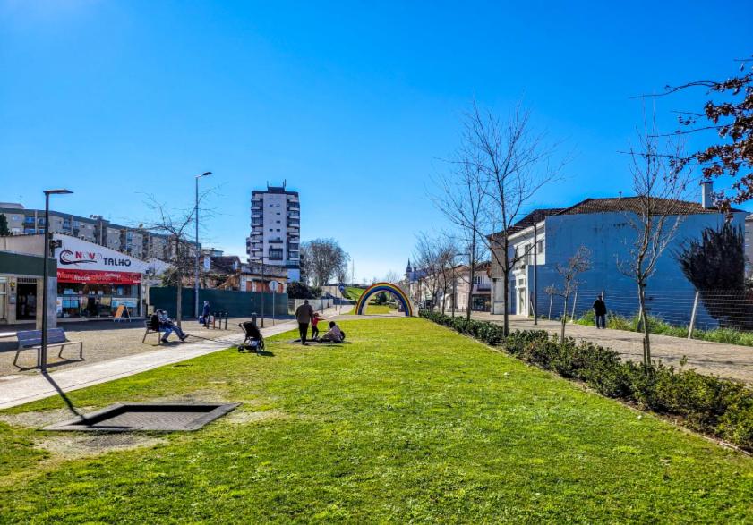 un parc avec des gens assis sur l'herbe dans une ville dans l'établissement Alameda Apartments, à Trofa
