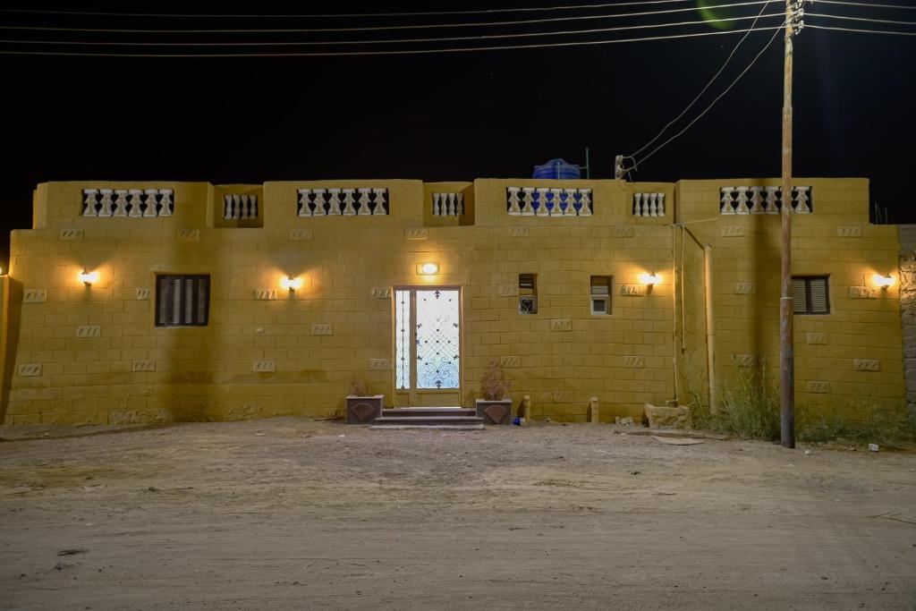 Un edificio de ladrillos amarillos con una puerta por la noche. en شاليه سيوة - Chalet Siwa, en Siwa