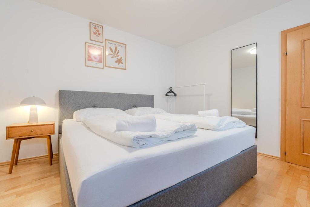 un lit avec des draps blancs et des oreillers dans une chambre dans l'établissement Whats-App Self-Check-IN - Bad Aussee City House, à Bad Aussee