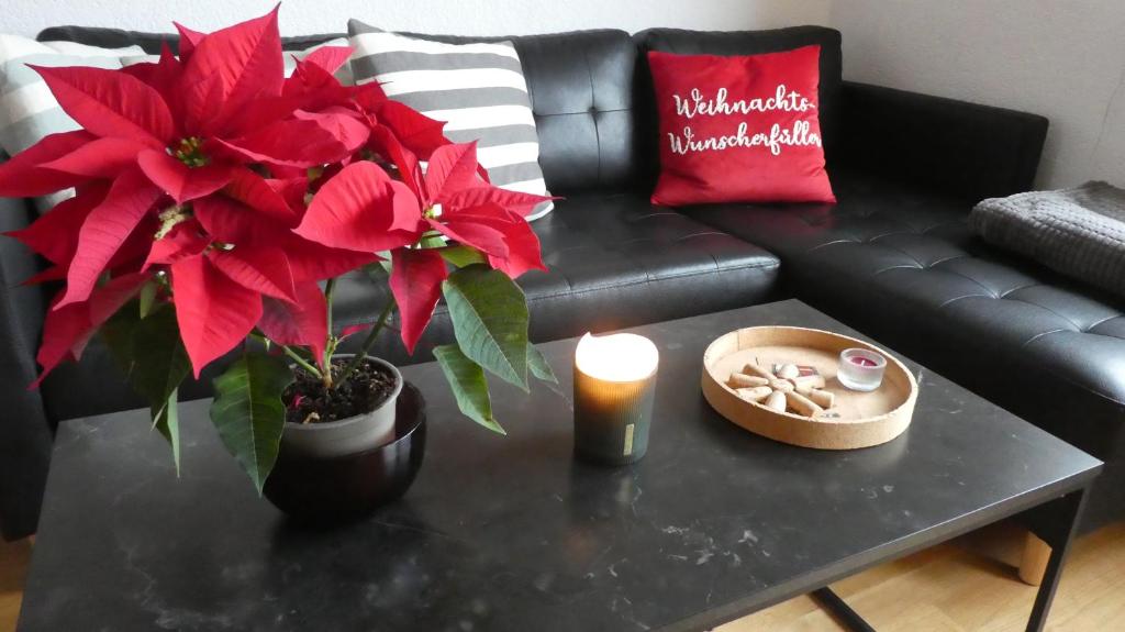 un tavolino da caffè nero con fiori rossi e una candela di Basti's Rooms&Breakfast - Self Checkin a Weil am Rhein