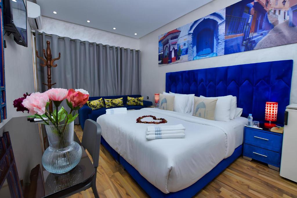 Hotel Dar Annasr في شفشاون: غرفة نوم بسرير ازرق مع إناء من الزهور