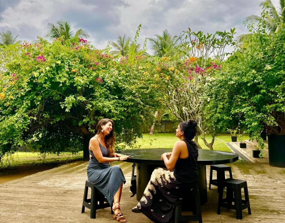 two women sitting at a table in a park at The Colony Hotel in Habaraduwa
