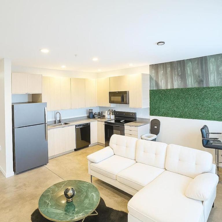 a living room with a white couch and a kitchen at Forestline Suite in Des Moines