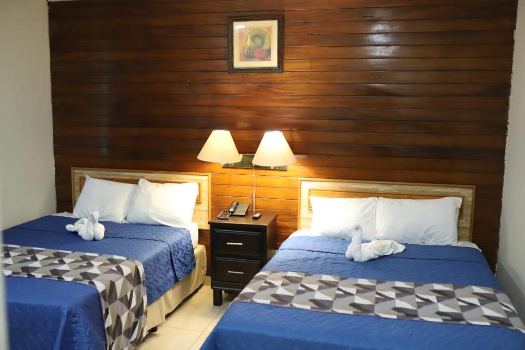 a hotel room with two beds with blue sheets at Hotel Mediterraneo Plaza in San Salvador