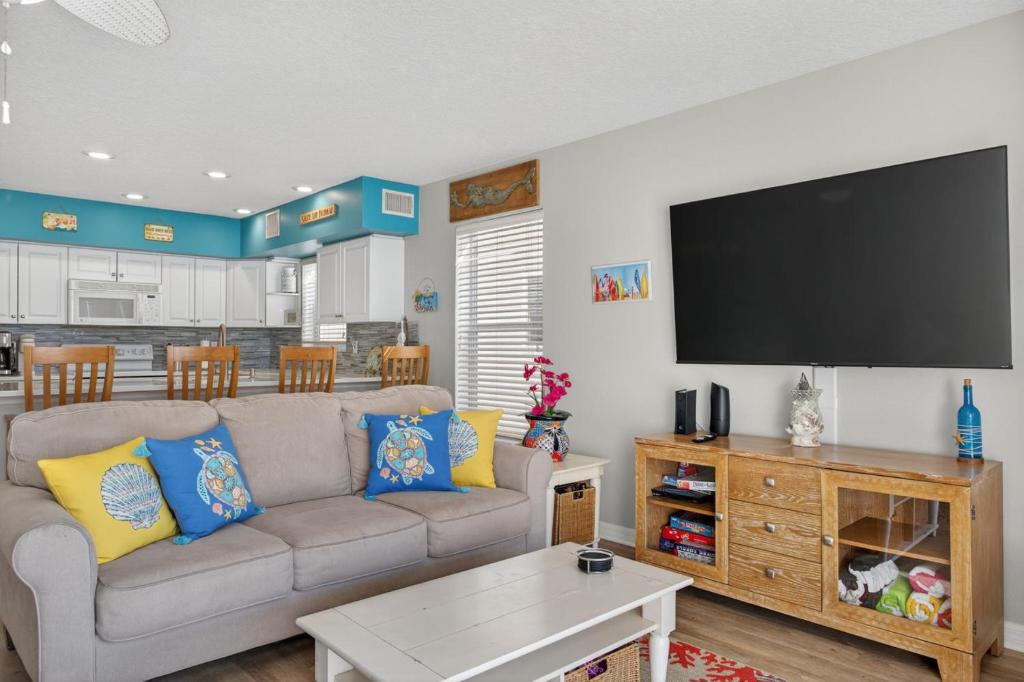 a living room with a couch and a flat screen tv at Captains Cove Unit 402 in Clearwater Beach
