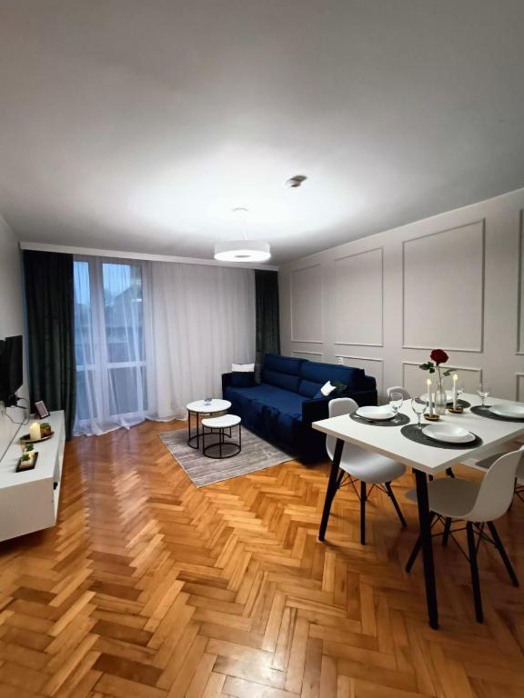 a living room with a blue couch and a table at Apartament Aksamitny in Toruń