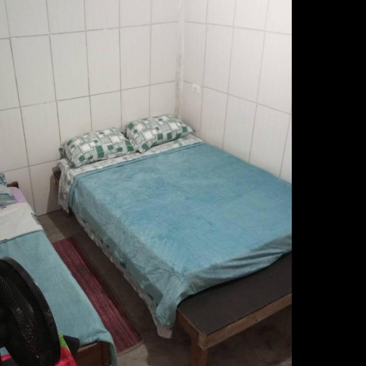 a small bedroom with a bed with a blue sheet at Cirlene e Lyncon in Paranaguá