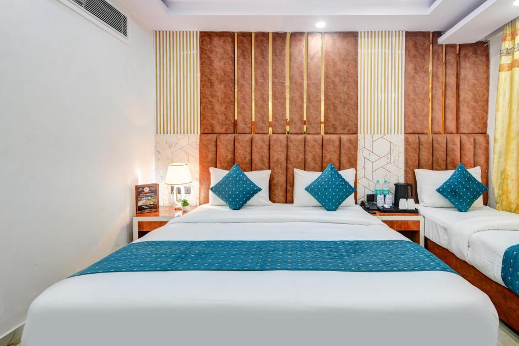 a bedroom with a large white bed with blue pillows at Hotel Ambience in New Delhi