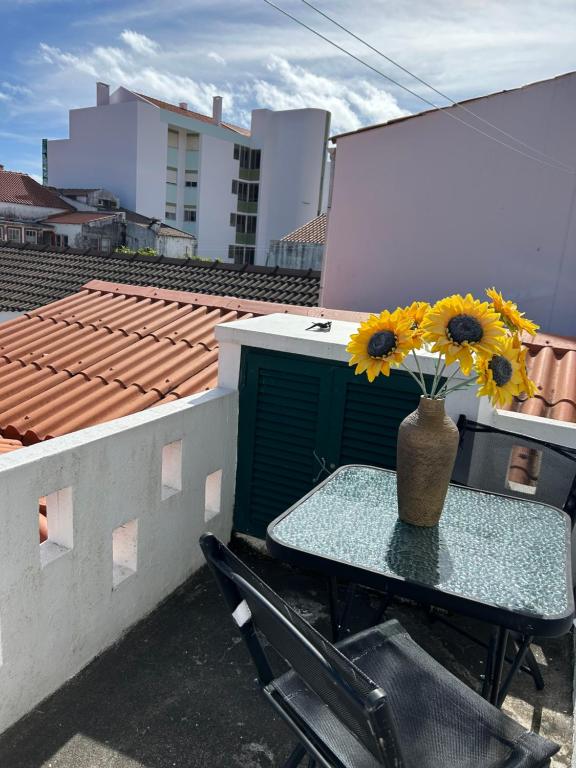 un tavolo con girasoli in un vaso su un balcone di GARDEN VIEW APARTMENT a Horta