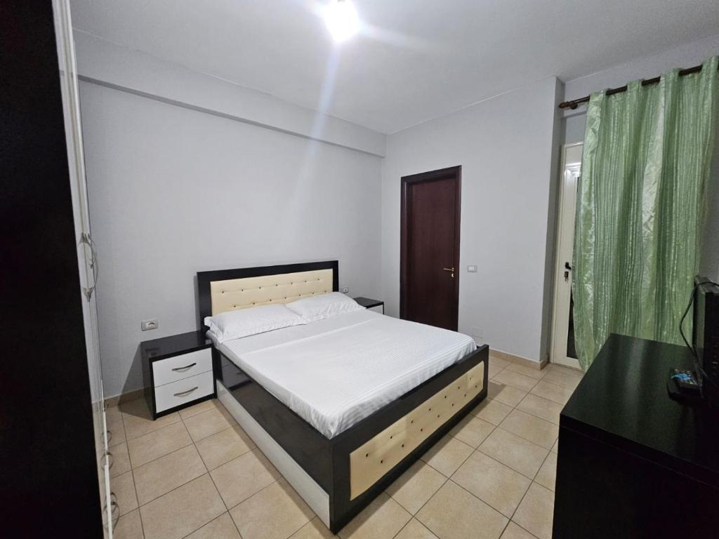 1 dormitorio con cama blanca y cortina verde en Apartamente Noel Vlore, en Vlorë