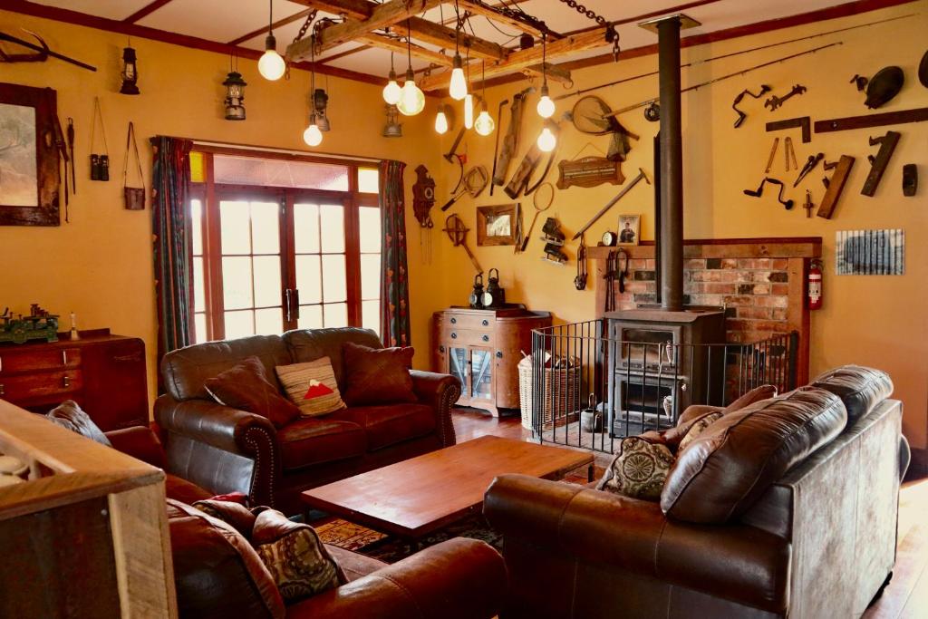 Tongariro Cottage - Hot Tub - Bring Your Dog! في Raurimu: غرفة معيشة مع أثاث من الجلد ومدفأة