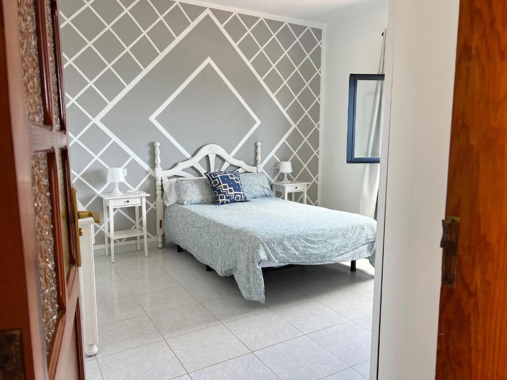 ein Schlafzimmer mit einem Bett mit einer geometrischen Wand in der Unterkunft casa el lajiar in Orzola