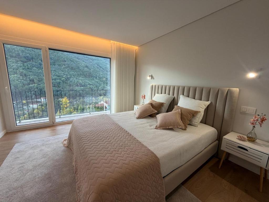 ein Schlafzimmer mit einem großen Bett mit einem großen Fenster in der Unterkunft Casa Maria Eduarda in Assureira