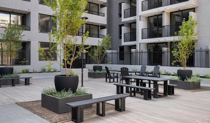 a courtyard with benches and trees in front of a building at Diseño y conectividad, tu espacio en Santiago in El Cerrillo