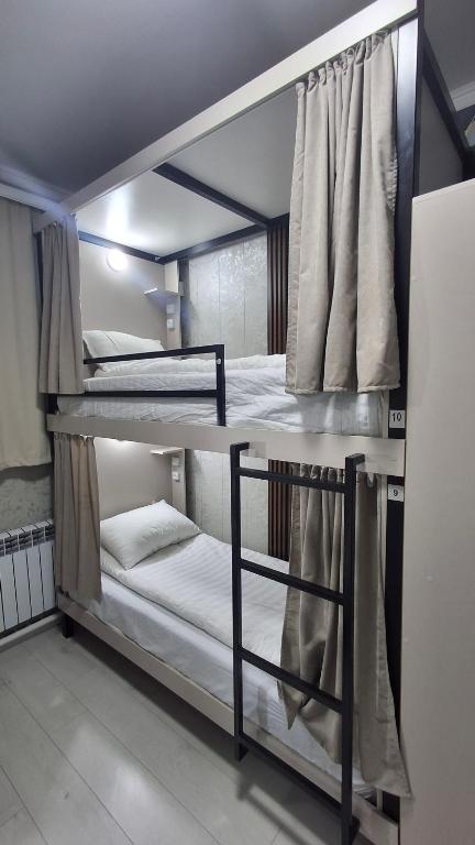 2 Etagenbetten befinden sich in einem Zimmer mit einem Fenster. in der Unterkunft AI Hostel in Bischkek