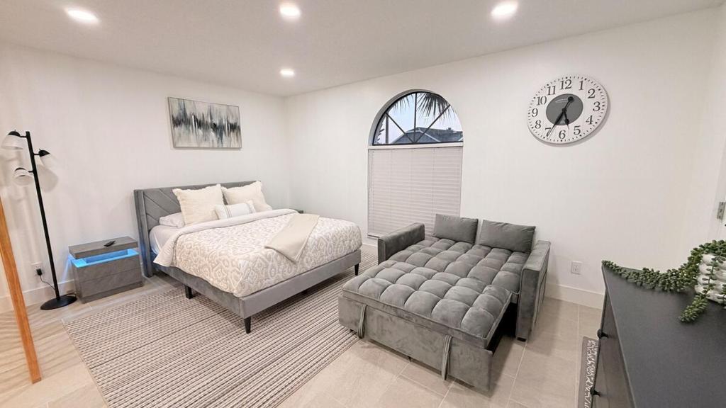a bedroom with a bed and a couch and a clock at Hermoso apartaestudio en Orlando in Orlando