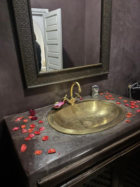 a bathroom sink with red petals on a counter at RIAD ALGHANI in Marrakech