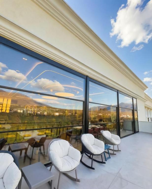a room with chairs and tables and windows at Leo Hotel in Kukës