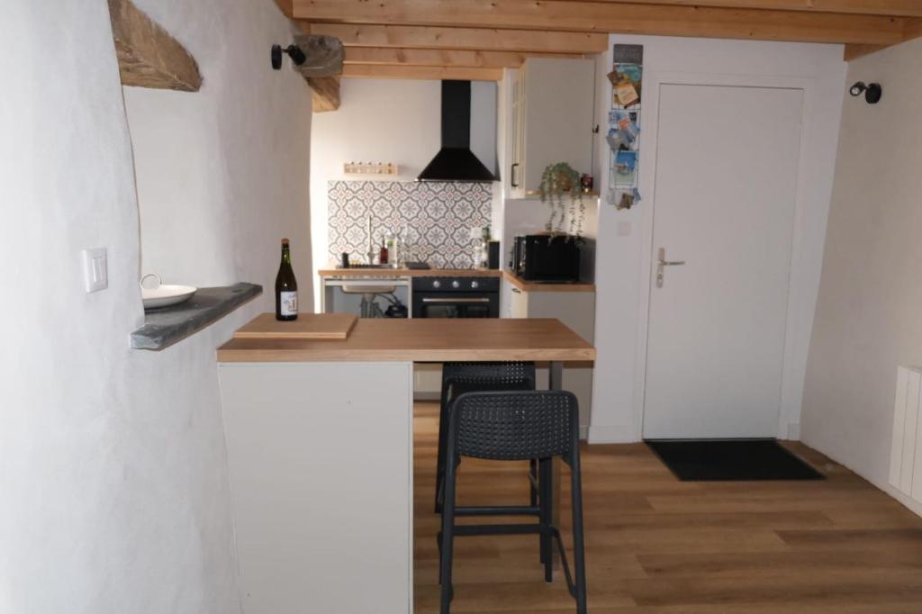 a kitchen with a counter and a bar with a stool at Les campanules in Lanvénec