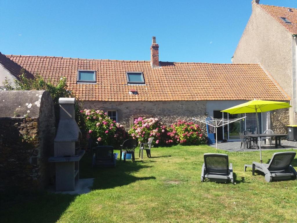 ein Haus mit einem Garten mit Stühlen und einem Sonnenschirm in der Unterkunft Villa Audresselles in Ambleteuse