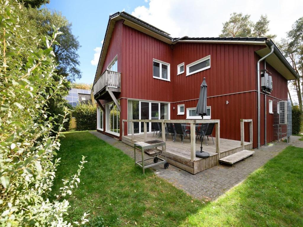 a red barn with a patio and an umbrella at XXL Familienferienhaus in Granzow