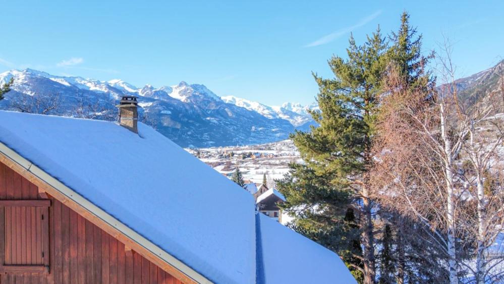 Un techo de granero cubierto de nieve con montañas al fondo en Chalet lumineux et spacieux entre Risoul Vars et les stations du Queyras, en Guillestre