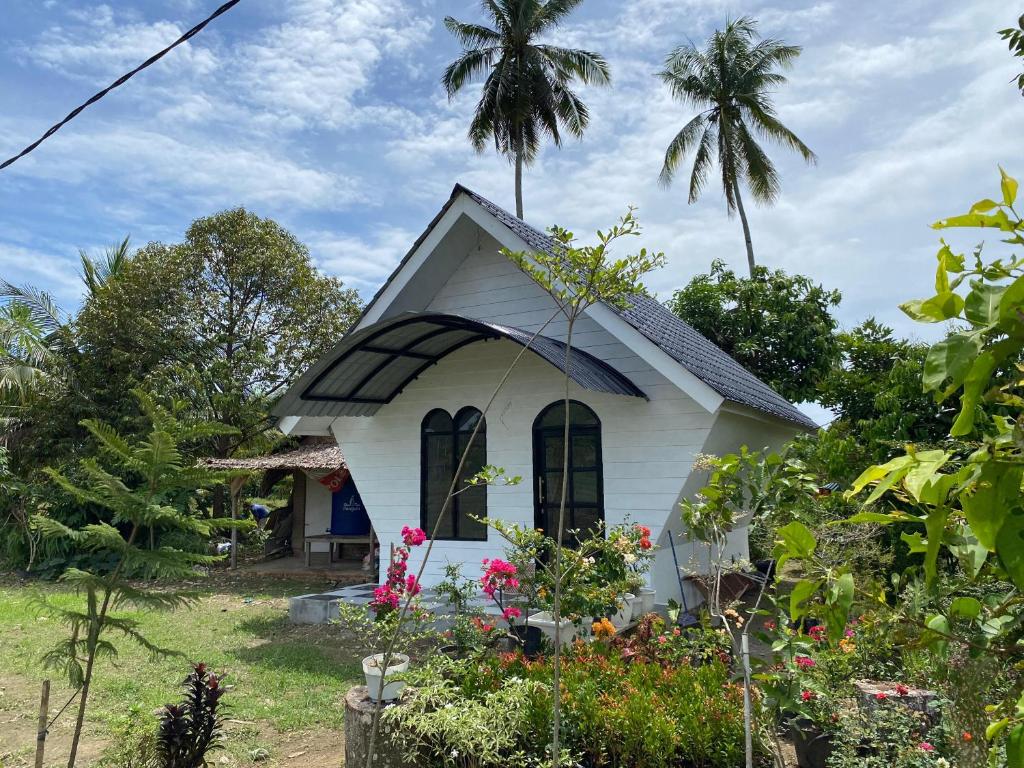 Djojo Bungalow في Timbanglawang: منزل أبيض صغير مع أشجار النخيل في الخلفية