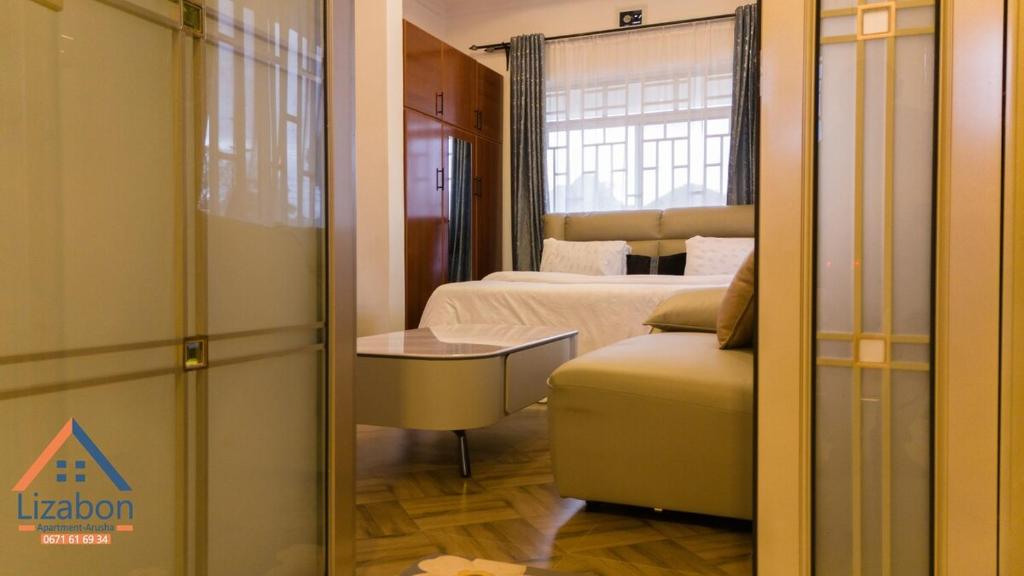 een kamer met een slaapkamer met een bed en een spiegel bij Lizabon Apartment Arusha in Nkoanrua