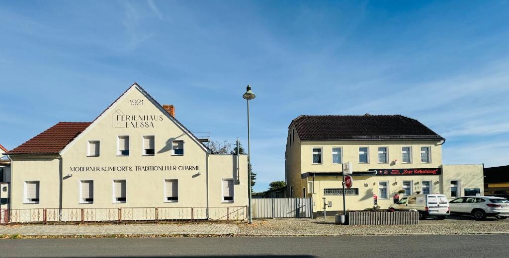 ein weißes Gebäude neben einem Gebäude mit einem Auto in der Unterkunft Ferienhaus Enessa in Lauchhammer