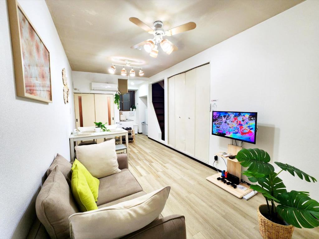 a living room with a couch and a flat screen tv at D,A-House OSAKA in Osaka