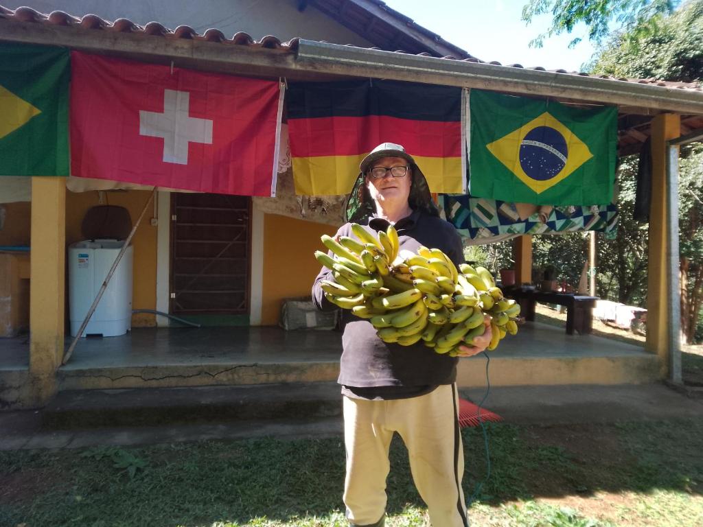 Eine Frau hält einen Bund Bananen vor einem Gebäude in der Unterkunft Casa Surpresa Europäisches Flair in São José dos Campos
