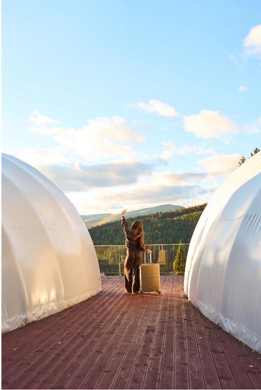 a person standing between two domes with a suitcase at Glamland in Yaremche