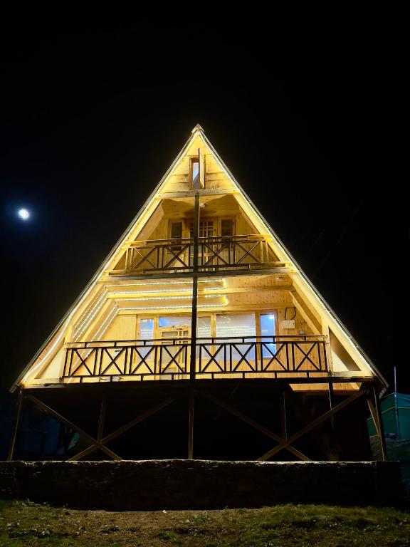 a large wooden house with a thatched roof at night at Crystal peak cottage in Nagar