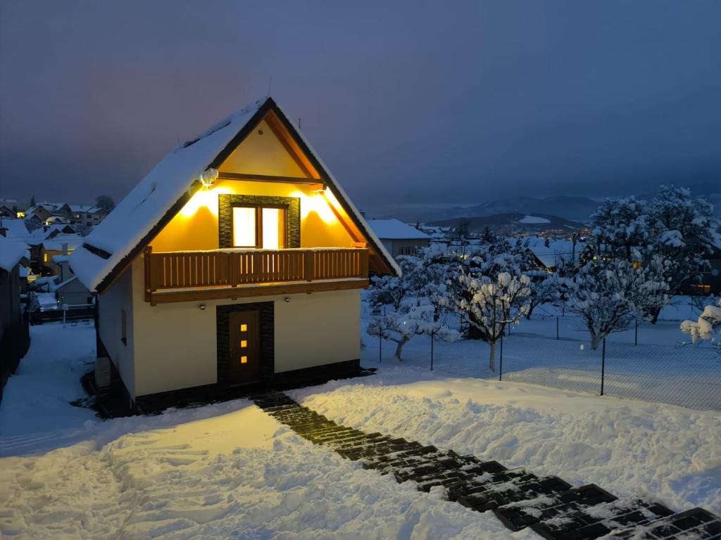 a house in the snow with lights on it at Chata Závažka in Závažná Poruba