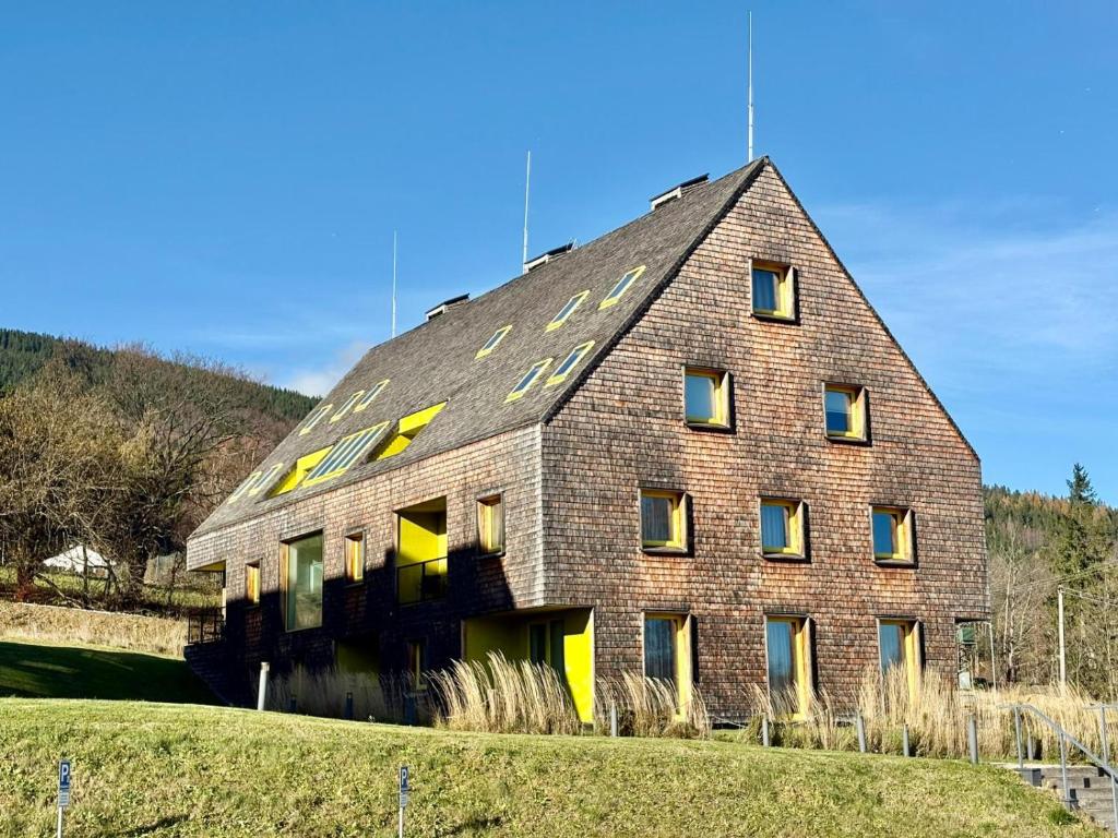 贝拉波德普拉德代姆Mezi vršky - rodinný apartmán Filipovice的山坡上有一栋大型砖砌建筑，窗户是黄色的。