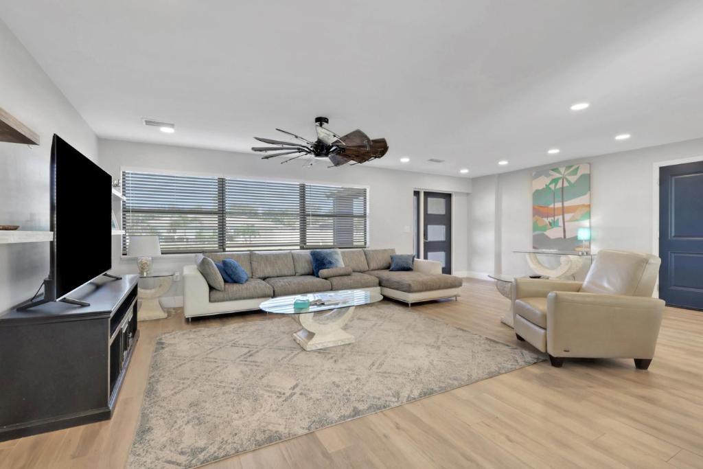 een woonkamer met een bank, een tv en stoelen bij 1 Block To Beach - Fully Upgraded Spacious & Quiet in Fort Myers Beach