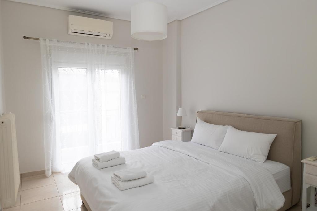 a white bedroom with a bed with towels on it at Santa Marina 9 In the center of Ioannina! in Ioannina