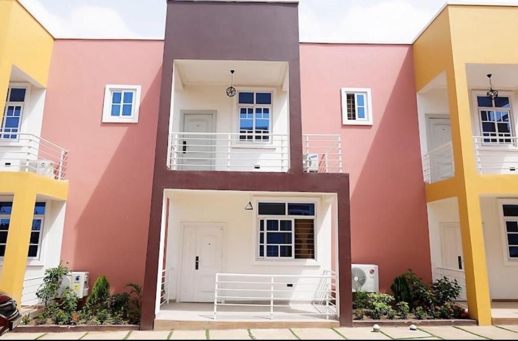 eine Fassade eines Gebäudes mit rosa und gelb in der Unterkunft Two Sisters Villa in Accra
