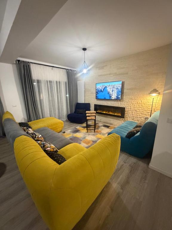 sala de estar con sofá amarillo y TV en Chill Boutique Zamora, en Buşteni